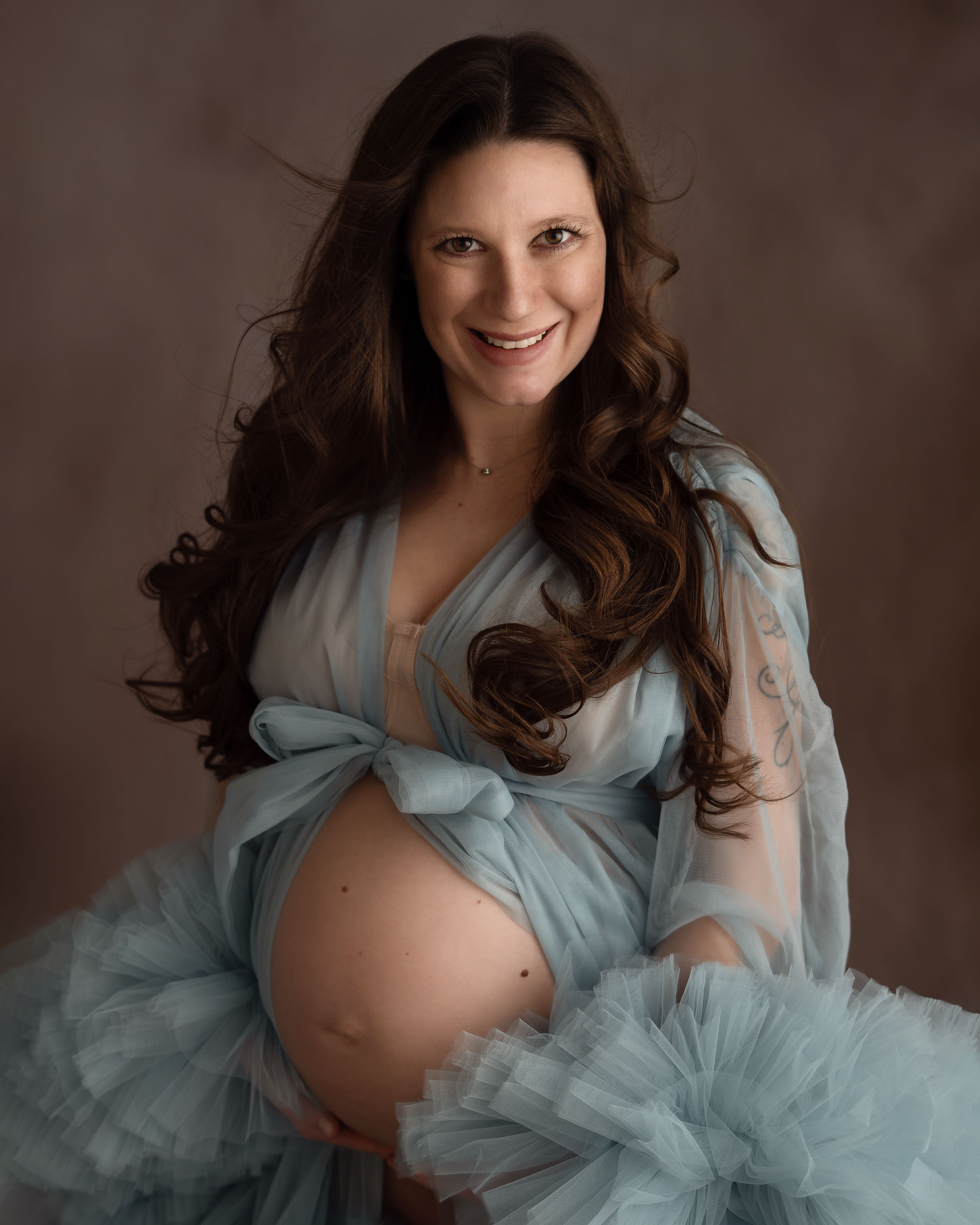 Schwangere Frau im blauem tull kleid die lacht