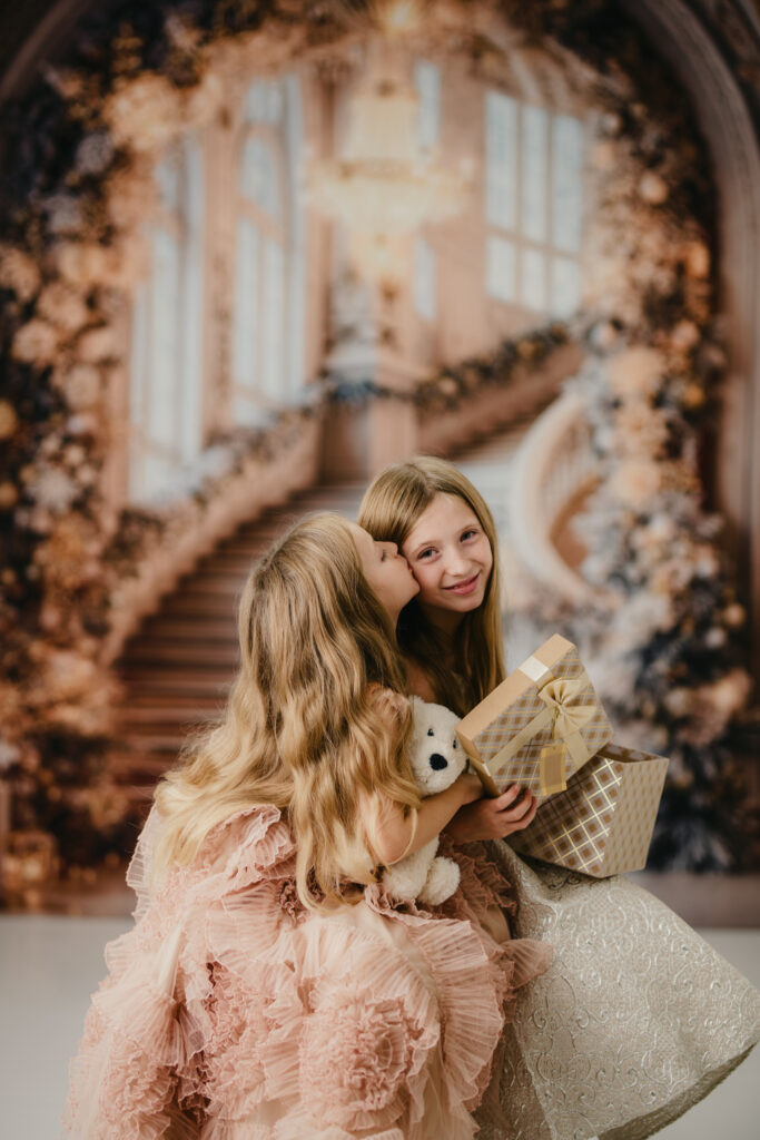 Weihnachtsshooting Reutlingen Studio – elegantes Fine-Art Portrait auf goldener Treppen-Kulisse, festlich geschmückt mit Lichtern und Dekoration, große Prinzessinnenkleider, luxuriöses Weihnachts-Fotoshooting love hugs